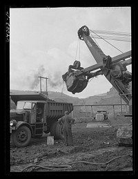 [Untitled photo, possibly related to: Loading trucks with iron ore at the Albany mine, Hibbing, Minnesota. This mine formerly used railroad until trucks were found more economical; they can climb the steep grade in much shorter time]. Sourced from the Library of Congress.