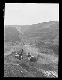 [Untitled photo, possibly related to: Loading trucks with iron ore at the Albany mine, Hibbing, Minnesota. This mine formerly used railroad until trucks were found more economical; they can climb the steep grade in much shorter time]. Sourced from the Library of Congress.