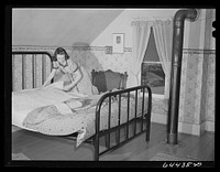 Meeker County, Minnesota. Elaine McCormick, one of the McRaith grandchildren, making the beds in the morning before the school bus comes. Sourced from the Library of Congress.