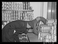 Williston, North Dakota. Inspecting used tire for sale (eight dollars and fifty cents) in grocery store. Sourced from the Library of Congress.