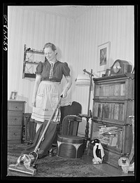 Wisdom, Montana. Mrs. Len Smith, using vacuum cleaner in her home. Sourced from the Library of Congress.