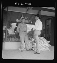 Farmers Exchange co-op hatchery store keeper talks over business with customer. Sourced from the Library of Congress.