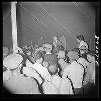 [Untitled photo, possibly related to: Batavia, New York. Elba FSA (Farm Security Administration) farm labor camp. Ray Mork, FSA official, addressing West Virginia migrants on the night of their arrival]. Sourced from the Library of Congress.