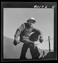Jess Richmond, pipe wrecker from Blackwell, Oklahoma by oil well being drilled in Goodrich field of the Continental oil company. Valley Center oil field near Wichita, Kansas. Sourced from the Library of Congress.