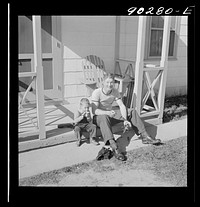 [Untitled photo, possibly related to: Radford, Virginia. Sunset Village, FSA housing project. Fred B. Williams from Savannah, Georgia, and his son "Buddy" cleaning the car distributer on the porch of his home. 803 9th Street]. Sourced from the Library of Congress.