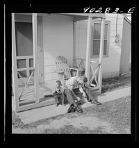 [Untitled photo, possibly related to: Radford, Virginia. Sunset Village, FSA housing project. Fred B. Williams from Savannah, Georgia, and his son "Buddy" cleaning the car distributer on the porch of his home. 803 9th Street]. Sourced from the Library of Congress.