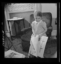 [Untitled photo, possibly related to: Washington, D.C. Scrap salvage campaign, Victory Program. This little girl folds the Sunday paper to take to school for contribution in the scrap collecting campaign]. Sourced from the Library of Congress.