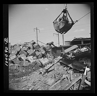 Washington, D.C. Scrap salvage campaign, Victory Program. Crane loads blocks of scrap metal onto a freight car in yard of wholesale junk company. Sourced from the Library of Congress.