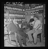 New York, New York. Rabbi in the Jewish section passing the time of day with the proprietor of a kosher wine shop where sacrificial wines are sold. Sourced from the Library of Congress.