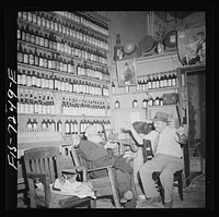 [Untitled photo, possibly related to: New York, New York. Rabbi in the Jewish section passing the time of day with the proprietor of a kosher wine shop where sacrificial wines are sold]. Sourced from the Library of Congress.