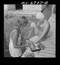 Interlochen, Michigan. National music camp where 300 or more young musicians study symphonic music for eight weeks each summer. Girls swimming during the recreation period. Applying first aid to girl who stubbed toe while in swimming. Sourced from the Library of Congress.