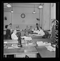 New York, New York. Newsroom of the New York Times newspaper. The "bull pen" where managing editors and others sit at one side. In foreground, assistant managing editor Rae. In background, managing editor James and night managing editor McCaw conferring. Sourced from the Library of Congress.