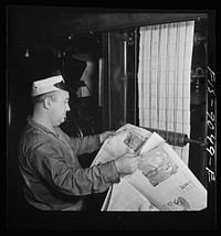 New York, New York. Pressroom of the New York Times newspaper. Pressman reading first edition as it comes off presses on conveyor, to detect defective press work. Sourced from the Library of Congress.