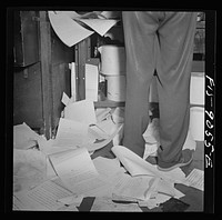 New York, New York. Wire room of the New York Times newspaper. All incoming dispatches are mimeographed, then passed through slot into news room for copy reading and editing. They have to be mimeographed so fast to meet the deadline that many copies fly out of the machine onto the littered floor. Sourced from the Library of Congress.