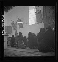 Trampas, New Mexico. Memorial mass at a church which was built in 1700 and is the best-preserved colonial mission in the Southwest. The altar in the center is a symbolic coffin. The congregation during the celebration of a mass. Sourced from the Library of Congress.