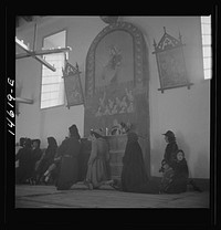 [Untitled photo, possibly related to: Trampas, New Mexico. Service at the mission church. The painting on the retablo represents Nuestra Senora del Carmel]. Sourced from the Library of Congress.