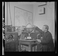 Questa, New Mexico. Father Smith broadcasting a news release in Spanish from his parish house broadcasting station. Sourced from the Library of Congress.