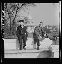 Washington, D.C. Soldier and a sailor on the steps of a monument in front of the Capitol on a Sunday. Sourced from the Library of Congress.