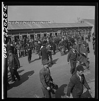 [Untitled photo, possibly related to: Baltimore, Maryland. Workmen of the second shift of the Bethlehem Fairfield shipyard lining up at the gate waiting to get on trolleys at three p.m.]. Sourced from the Library of Congress.