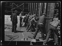 Building the SS Frederick Douglass. More than 6,000  shipyard workers are employed at the Bethlehem-Fairfield shipyards, where the Liberty ship is being rushed to completion. The noted orator and abolitionist leader worked as a ship caulker in the vicinity of this yard before he escaped from slavery. Men setting bulkhead in place, running from tank deck to flat deck in aft of ship. Sourced from the Library of Congress.