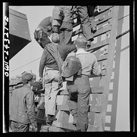 Bethlehem-Fairfield shipyards, Baltimore, Maryland. Workers on a ladder at the outfitting pier. Sourced from the Library of Congress.