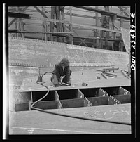 Bethlehem-Fairfield shipyards, Baltimore, Maryland. Chipper removing the welding beads where a lifting clip has been on an innerbottom unit. Sourced from the Library of Congress.