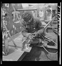 [Untitled photo, possibly related to: Bethlehem-Fairfield shipyards, Baltimore, Maryland. Burning a hole in a lifting ship]. Sourced from the Library of Congress.