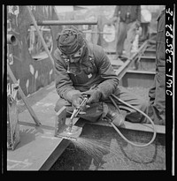 Bethlehem-Fairfield shipyards, Baltimore, Maryland. Burning a hole in a lifting ship. Sourced from the Library of Congress.