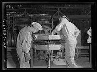 Holabird ordnance depot, Baltimore, Maryland. In the recapping shop, after the application of camelback, the tire is placed in a mold and is "cured" for about one hour and forty-five minutes. Here soldiers are removing it from the mold; as soon as it has cooled it is ready for use. Sourced from the Library of Congress.