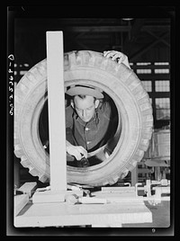 Holabird ordnance depot, Baltimore, Maryland. A soldier cementing the inner side wall of a truck tire; he is preparing this tire for sectional repair in the recapping shop. Sourced from the Library of Congress.