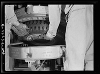 Holabird ordnance depot, Baltimore, Maryland. In the recapping shop, after application of camelback, the tire is placed in a mold where it is "cured" for about an hour and forty-five minutes. Here soldiers are removing it from the mold; as soon as it is cool it is ready for use. Sourced from the Library of Congress.