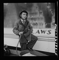 Buffalo, New York. Peter Grimm, age ten, waiting with his wagon outside Loblaw's grocery store for customers to ask him to deliver their groceries. This was a rainy day with few customers. Sometimes Peter makes as much as three dollars on a Saturday. He pays for all his school supplies and much of his clothing. His mother, a twenty-six year old widow, is a crane operator at Pratt and Letchworth. Sourced from the Library of Congress.