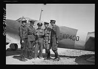 Somewhere in Iran. Major General Lewis Brererton in the center, the Commander of the United States Army force in the Middle East, with a group of Russian officers standing before an American warplane delivered to the Russians. A United States warplane is being tested in the background and bears the red star insignia of Russia, which is made by filling in the white star of the United States with red paint. Sourced from the Library of Congress.