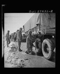 Somewhere in the Persian corridor, a United States Army truck convoy carrying supplies for the aid of Russia. An Iranian boy giving the American driver a helping hand at putting on chains before the trucks go into a snow bound pass through the mountains. Sourced from the Library of Congress.