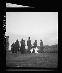 Somewhere in the Persian corridor. A United States Army truck convoy carrying supplies for Russia. Truck drivers standing around a fire after the tough drive through a snowbound mountain pass. Sourced from the Library of Congress.