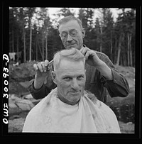 Spring pulpwood drive on the Brown Company timber holdings in Maine. Camp handy man is conveniently handy with the scissors; the nearest professional barber is thirty-five miles away. Sourced from the Library of Congress.