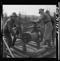 [Untitled photo, possibly related to: Spring pulpwood drive on the Brown Company timber holdings in Maine. Woodsmen winching up the boom on Long Pond; during the night the wind has blown the logs in the boom up pond away from the dam through which they must be sluiced]. Sourced from the Library of Congress.