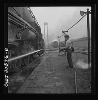 Pitcairn, Pennsylvania. Mrs. Bernice Stevens of Braddock, Pennsylvania, mother of one child, employed in the engine house of the Pennsylvania Railroad, earns fifty-eight cents per hour. She is cleaning a locomotive with a high pressure nozzle. Mrs. Stevens' husband is in the U.S. Army. Sourced from the Library of Congress.