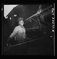 Pitcairn, Pennsylvania. Mrs. Bernice Stevens of Braddock, Pennsylvania, mother of one child, employed in the engine house of the Pennsylvania Railroad, earns fifty-eight cents per hour. She is cleaning a locomotive with a high pressure nozzle. Mrs. Stevens' husband is in the U.S. Army. Sourced from the Library of Congress.