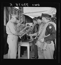 Bar Harbor, Maine. Civil Air Patrol base headquarters of coastal patrol no. 20. Base commander Major James B. King making a routine inspection of "Mae West" life preservers. Sourced from the Library of Congress.