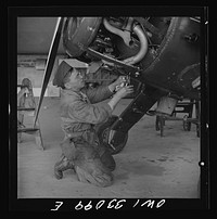 Bar Harbor, Maine. Civil Air Patrol base headquarters of coastal patrol no. 20. Ground crew mechanic making repairs on a patrol plane in the hangar. Sourced from the Library of Congress.