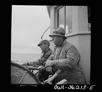 On board a fishing vessel out from Gloucester, Massachusetts. Winch control men intent on seeing to it that the proper amount of cable is let out at the proper spot. Sourced from the Library of Congress.