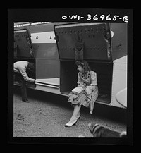 [Untitled photo, possibly related to: A girl passenger sitting in a baggage compartment while she is waiting for the driver to finish unloading the bags from a Greyhound bus that broke down at a small town in Pennsylvania]. Sourced from the Library of Congress.