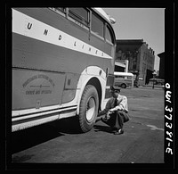 Columbus, Ohio. Randy Pribble, a bus driver for the Pennsylvania Greyhound Lines, Incorporated, checking tires on a bus by thumping them before taking it out on a run. Since there are two tires on the back, the sound is the best way of telling if one is flat. Sourced from the Library of Congress.