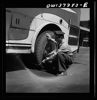 Columbus, Ohio. Randy Pribble, a bus driver for the Pennsylvania Greyhound Lines, Incorporated, checking tires on a bus by thumping them before taking it out on a run. Since there are two tires on the back, the sound is the best way of telling if one of them is flat. Sourced from the Library of Congress.