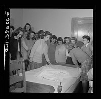 Washington, D.C. Home management students at Woodrow Wilson High School giving a demonstration in bedmaking. There is a model bedroom, living room, kitchen, and laundry for use by home economics students. Sourced from the Library of Congress.