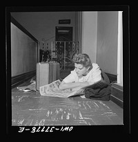 Louisville, Kentucky. A bus passenger reading the Sunday comics, which, since all the benches were full, she spread on the floor to sleep on while waiting from 11 p.m. to 8 a.m. for a bus in the Greyhound bus station. She is on her way to Nebraska to enroll in a nursing school. Sourced from the Library of Congress.