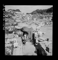 During the first few days after the Germans had been driven from Sicily, the people were obliged to live in makeshift homes, such as this ancient Roman amphitheatre. Now they are returning to their own homes, rebuilding, refurbishing, and starting life anew. Sourced from the Library of Congress.