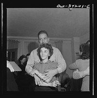 [Untitled photo, possibly related to: Washington, D.C. Serviceman and a girl looking at pictures at a party]. Sourced from the Library of Congress.