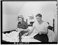 Washington, D.C. In the evening, Hugh Massman and his wife fold diapers. Joey's bureau drawer crib is moved to the side of their bed for the night. Sourced from the Library of Congress.